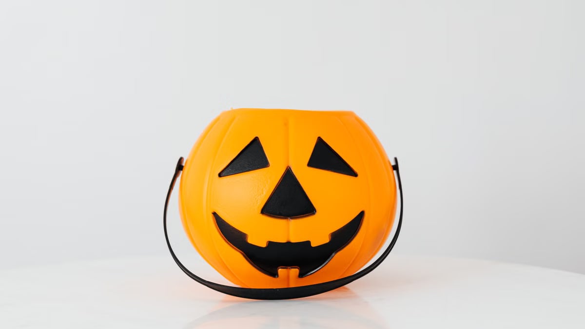 Bright orange pumpkin bucket for Halloween, perfect for trick-or-treat candy collection.